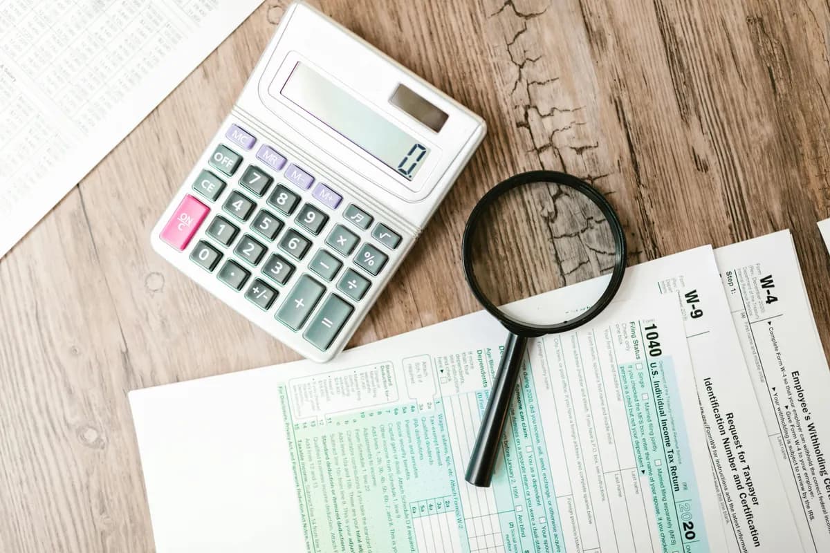 Financial statement audit services — calculator, magnifying glass, and tax forms on a desk